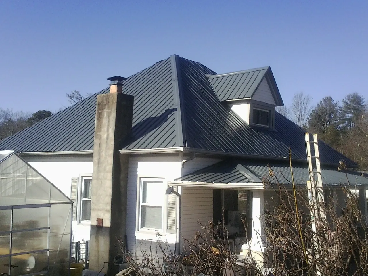 Dark blue standing seam metal roof on a white farmhouse with dormer — Slate & Tile Roof Repair by Roofing Brothers in Naselle