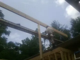 Carpenter setting a ridge beam over a new addition frame — Ice Dam Removal by Roofing Brothers in Naselle