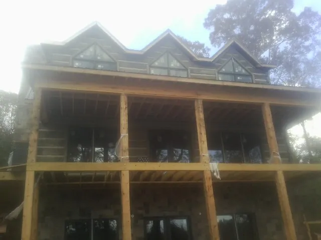 Dormers and porch framing on a large log home under construction — Roof Coating work by our crew in Naselle