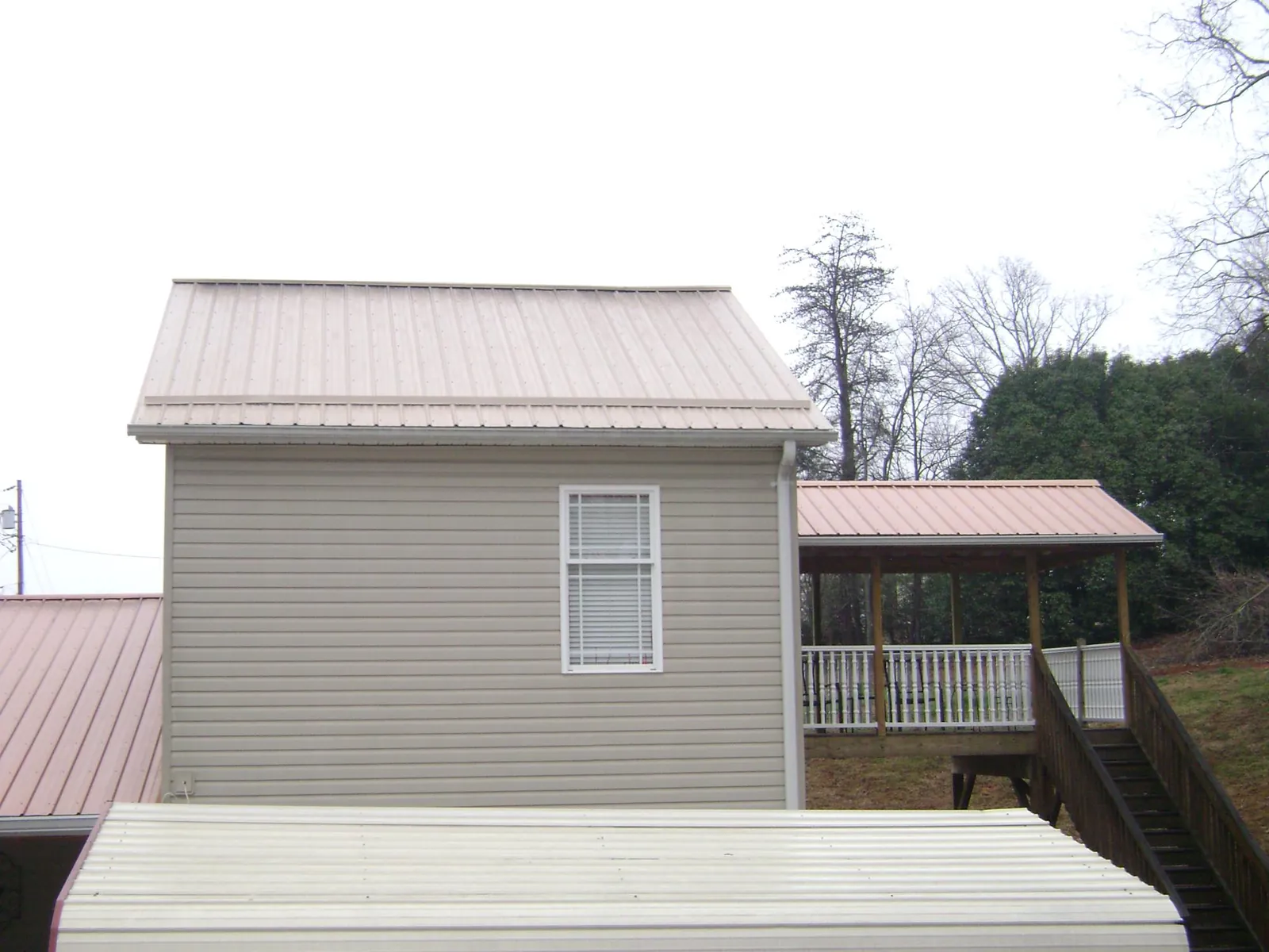 Tan metal roofs on a two story addition and attached porch, from a Roof Replacement job in Naselle