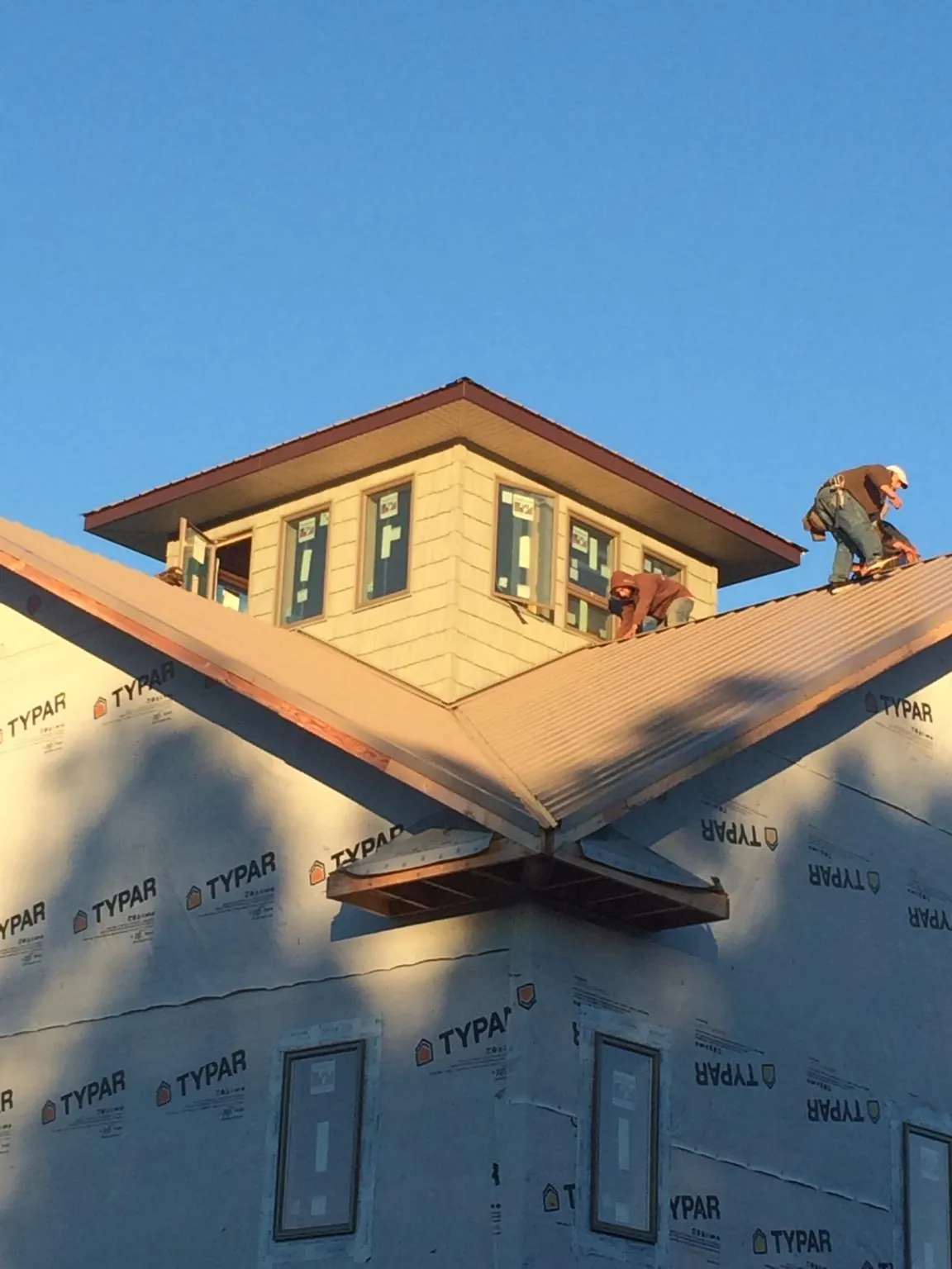 Roofers working around a rooftop cupola on a new metal roof at sunset — Roof Waterproofing in Naselle by Roofing Brothers